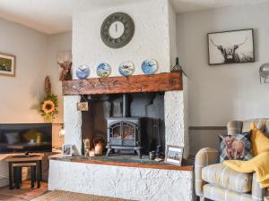 a living room with a fireplace with a clock on the wall at Elms Cottage - Sadberge in Long Newton