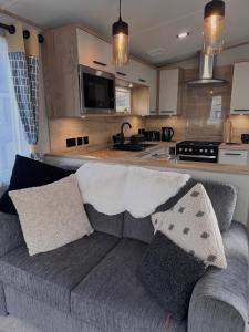 a living room with a couch and a kitchen at Sheepfold lodge in Sedbergh