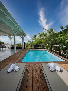 una piscina con dos toallas en una terraza de madera en Villa Migaline, stunning bay views, en Le Marin