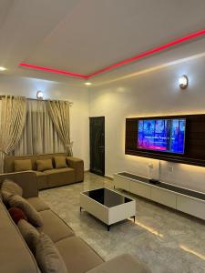 Una sala de estar con sofás y un televisor de pantalla plana. en Jahi Apartments, en Kadobunkuro