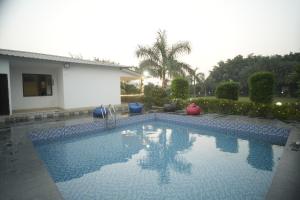 a swimming pool in a yard next to a house at Blue Heaven Farm Villa in Noida +18 photos