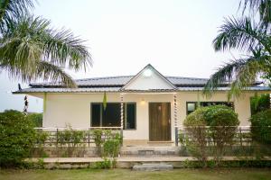 a house with palm trees in front of it at Blue Heaven Farm Villa in Noida +7 photos