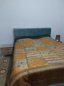 een bed met een quilt erop in een kamer bij Location saisonnière entre mer, forêt et calme in Raʼs al Jabal