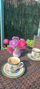 zwei Tassen und Teller auf einem Tisch mit Blumen in der Unterkunft Casa cu gradina in Văleni