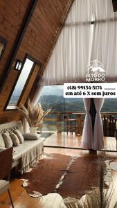 a living room with a couch and a large window at Chales alto do morro 1, conforto e vista privilegiada in Rancho Queimado