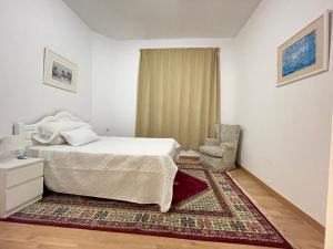 セビリアにあるArce apartamentosのベッドと椅子のある白い寝室