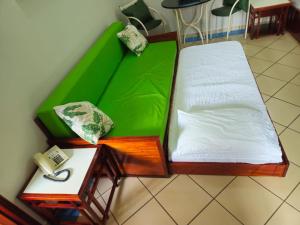 a room with a green bed and a table with a phone at Apto Residencial Aconchego2 em Rio Quente Go - Hot Park in Rio Quente