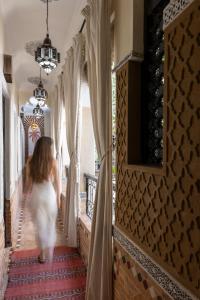 a woman in a white dress walking down a hallway at Riad Arabesque in Marrakech