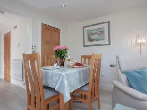 a dining room with a table and chairs with flowers on it at The Linhay in Durleigh