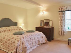 a bedroom with a bed with a dresser and a mirror at Laundry Cottage in Uldale