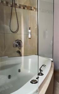a white bath tub with a glass shower door at Alfa Hotel in Piraeus +42 photos