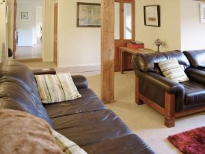 a living room with a leather couch and a table at Swallows Cottage in Tipton Saint John