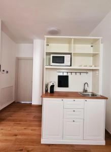 une cuisine blanche avec un évier et un micro-ondes dans l'établissement La Casa di Nonna, à Conversano