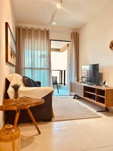 un soggiorno con un divano, una TV e un tavolo di FLAT Beira Mar Tamandare a Tamandaré