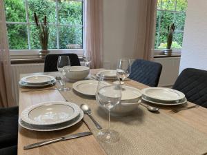 a wooden table with plates and wine glasses on it at Ferienwohnung Dorfliebe Minden by Engelmann in Minden