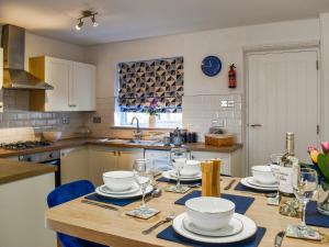 eine Küche mit einem Tisch mit Tellern und Weingläsern in der Unterkunft Cayton Cove Cottage in Cayton + 8 Fotos