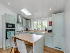 a kitchen with white cabinets and a wooden table at Fuchsia Lodge in Willington +19 photos