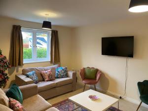 ein Wohnzimmer mit Sofa und Fernseher in der Unterkunft Warm & Cosy 4 Bed Cambridge House w Parking Garden & High Speed WIFI in Milton