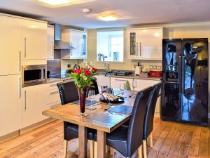 a kitchen with a wooden table and black appliances at Annie Oswalds Cottage in Lucker