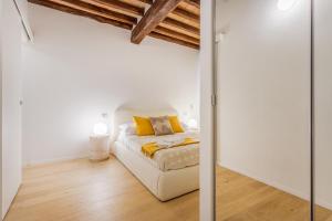 a bedroom with white walls and a bed with yellow pillows at Nebbia sul Naviglio - Rua Frati 34 - Boutique Apartment in Modena