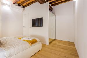 a bedroom with a bed and a tv on the wall at Nebbia sul Naviglio - Rua Frati 34 - Boutique Apartment in Modena