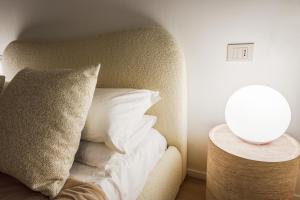 a bed with a pillow and a lamp on a table at Fumo di Lambrusco - Rua Frati 34 - Boutique Apartment in Modena