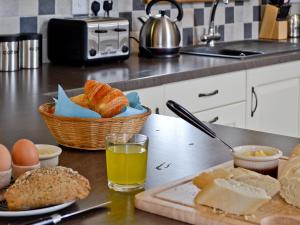 een tafel met een mandje brood en eieren en een glas sap bij Llanlliwe Cottage in Henllan Amgoed