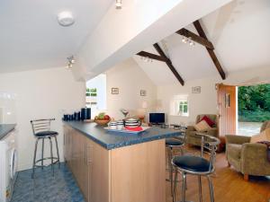 eine Küche mit einer Theke und Hockern in einem Zimmer in der Unterkunft Lower Bushford Cottage in Talbenny