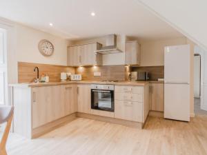 eine Küche mit Holzschränken und einem weißen Kühlschrank in der Unterkunft Dalnaglar Cottage - Uk30260 in Cray