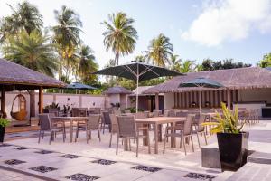 a restaurant with tables and chairs and umbrellas at Reveries Maldives in Gan