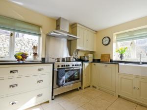 a kitchen with white cabinets and a stove top oven at Hungate Garden Cottage in Pickering