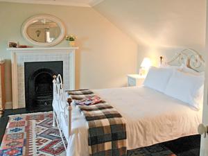 Schlafzimmer mit einem Bett, einem Kamin und einem Spiegel in der Unterkunft The Cottage in Garlieston