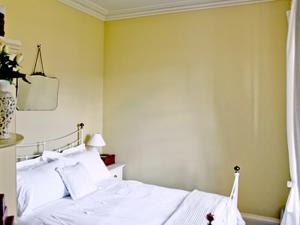 ein Schlafzimmer mit einem weißen Bett und einer gelben Wand in der Unterkunft The Cottage in Garlieston + 8 Fotos