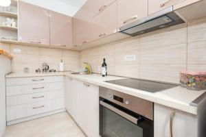 a kitchen with white cabinets and a sink and a stove at GALIOT Apartment in Škaljari