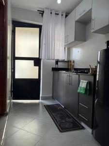 eine Küche mit einer schwarzen Tür und einem Küchenteppich in der Unterkunft Solara Loft in Nairobi + 1 Foto