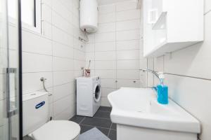 a white bathroom with a toilet and a sink at GALIOT Apartment in Škaljari
