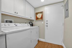 a kitchen with white cabinets and a washer and dryer at Direct Oceanfront Three-Bedroom Luxury Apartment with Large Terrace in South Palm Beach