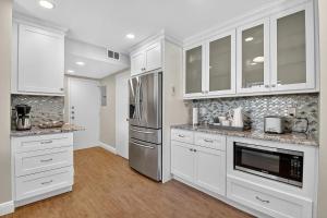 a kitchen with white cabinets and stainless steel appliances at Direct Oceanfront Three-Bedroom Luxury Apartment with Large Terrace in South Palm Beach +37 photos