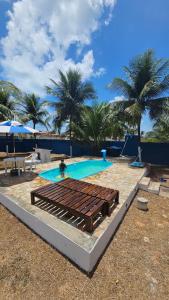 ein Swimmingpool mit Palmen im Hintergrund in der Unterkunft Casa de praia com área de lazer in Nísia Floresta