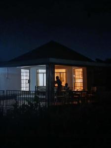 two people sitting at a table in a house at night at Victoria Stay in Jinja