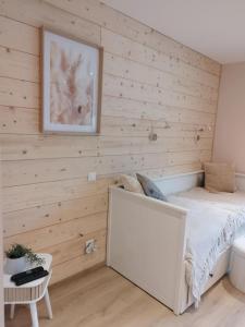 ein Schlafzimmer mit Holzwänden mit einem Bett und einem Bild in der Unterkunft Parenthèse Vosgienne in Cornimont