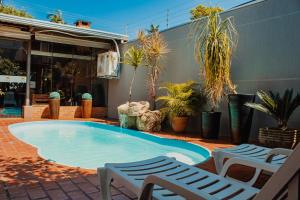 a large swimming pool with two chairs and plants at Pousada Nanai in Foz do Iguaçu