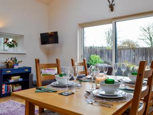a wooden table with plates and wine glasses on it at Birch Tree Cottage in Edzell