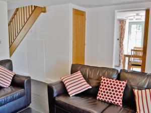 Eglwys-FâchにあるHen Dyのリビングルーム(赤と白の枕を使用した茶色の革張りのソファ付)