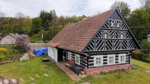 an old house with a black and white roof at Poloroubenka Podkrkonoší in Bělá