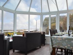 een serre met een tafel, stoelen en ramen bij Isle View - 28284 in Broadford
