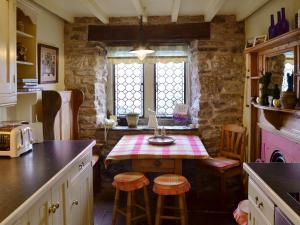 a kitchen with a table and stools in a room at Mullions Cottage in Castleton
