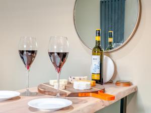 a table with two glasses of red wine and a mirror at Vitamin Sea Residency in Herne Bay