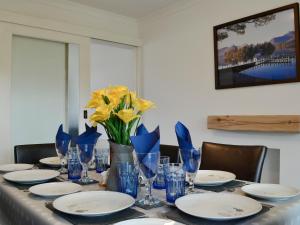 a table with blue glasses and yellow flowers on it at Hillside Cottage in Keswick
