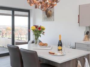 eine Küche mit einem Tisch mit einer Flasche Wein und Blumen in der Unterkunft The Hideaway -Ukc3844 in Ticknall